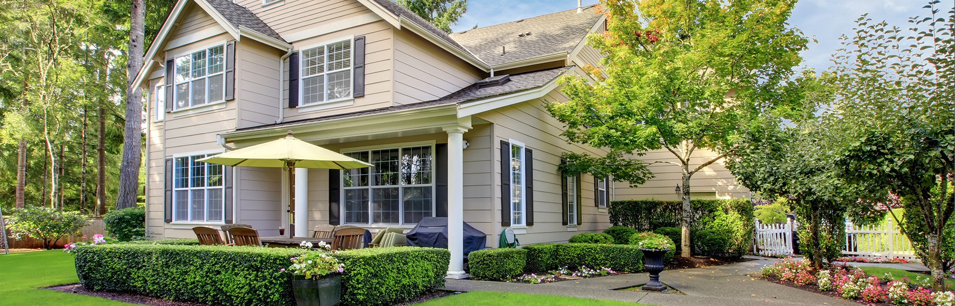 tan house with manicured lawn and shrubs 